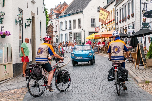 Fietsers in het centrum van Thorn met een oldsmobile die tegemoet komt